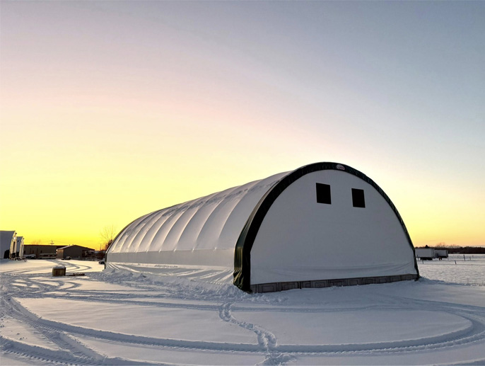 Bâtiment en toile avec charpente d’acier galvanisé en hiver au coucher du soleil