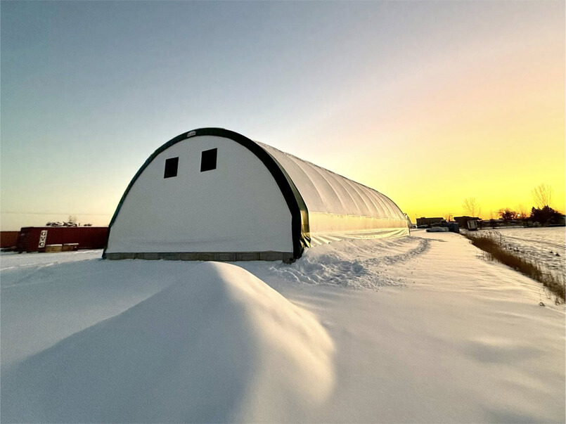 Bâtiment en toile avec charpente d’acier galvanisé recouvert de neige en hiver